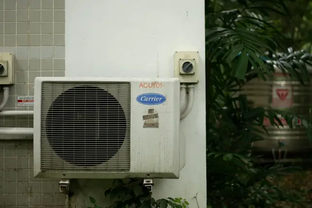 Condensadora Carrier instalada numa parede externa de azulejo, ao lado de folhagens