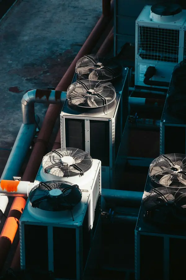 Vista de cima de várias condensadoras industriais lado a lado num telhado, com ventiladores e tubulação